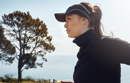 Focused minds get further. a determined young woman going for a jog on her own with a view of the city in the background.の写真素材