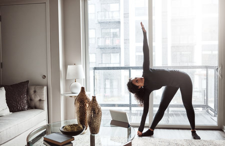 Finding the balance. a focused young woman doing a yoga pose from the comfort of home inside during the day.の写真素材