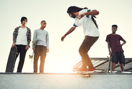 He always has a new trick to show us. Full length shot of a group of friends skating together on their skateboards at a skatepark.の写真素材
