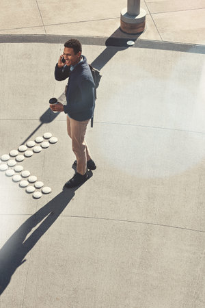 When business calls, go to it. a young businessman using a mobile phone while walking through the...