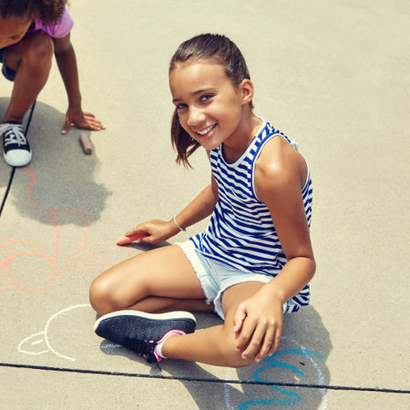 Getting creative with chalk. adorable little girls drawing with chalk on the pavement outdoors.の写真素材