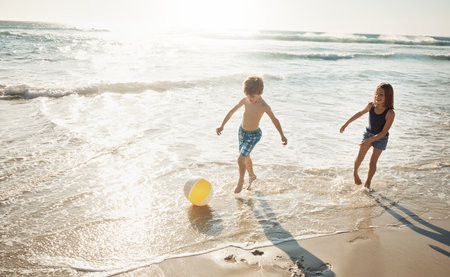 The kids are always up for a beach day. a little brother and sister playing together on the beach.の写真素材