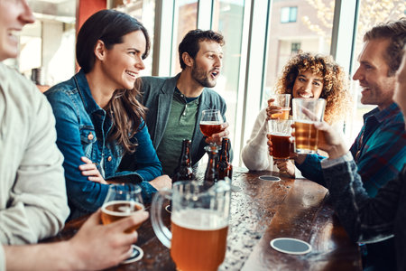 Were always down for a beer and good company. young people having beers at a bar.の写真素材