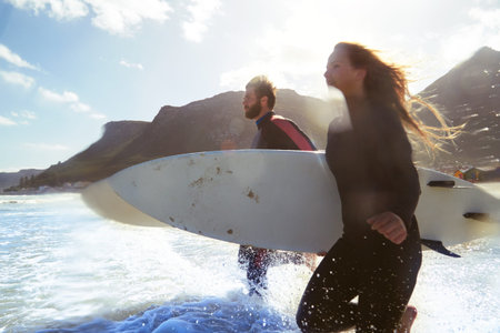 They live for this. an athletic young couple surfing at their favourite beach.の写真素材