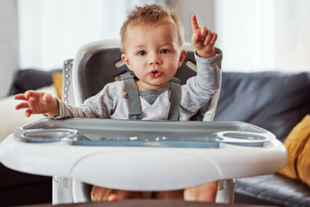 Hes quite the picky eater. a cute little baby boy sitting in his feeding chair.