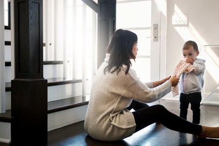 Give it to mommy, please. a young woman trying to remove a cloth from her daughter.の写真素材