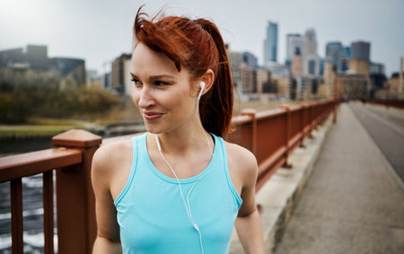 Its a great day for a run. a sporty young woman listening to music while out for a run in the city.