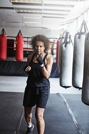 Youre a fighter not a quitter. a female kick-boxer training at the gym.の写真素材