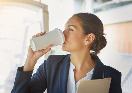 Loving her morning commute. a young businesswoman drinking coffee while on her way to the office.の写真素材
