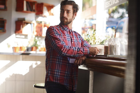 He found the perfect hang out spot. a young man having a cup of coffee in a cafe.の写真素材