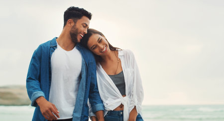 I found my home in him. an affectionate young couple holding hands and walking along the beach...