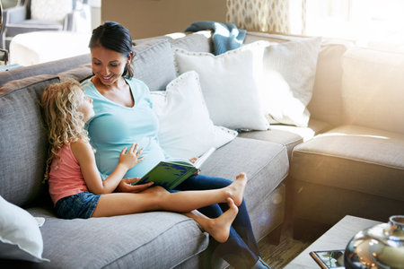 I cant wait to meet him. a pregnant woman spending time with her daughter at home.の写真素材