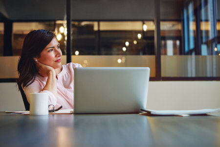 Maybe its time for a career change...a businesswoman daydreaming while working on a laptop in an office.の写真素材
