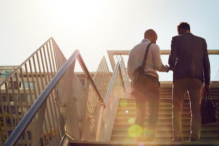 Entrepreneurs on the move. Rearview shot of unrecognizable businessmen walking up stairs outside.の写真素材