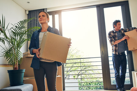 More hands make less work. a focused middle aged couple packing out a boxes at their new home inside during the day.の写真素材