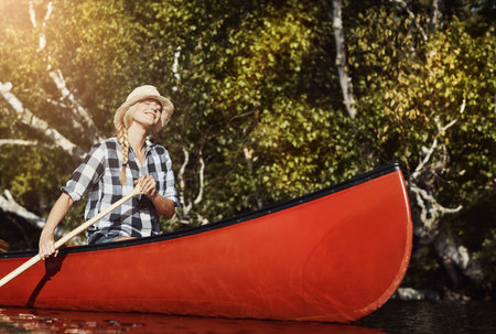 Keeping her adventurous spirit alive. an attractive young woman spending a day kayaking on the lake.の写真素材