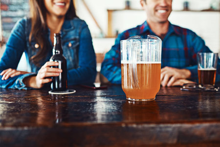 Lets have another. an unrecognizable couple enjoying a drink at a bar.