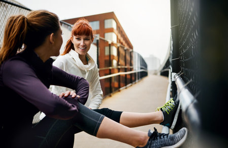 Catching up while stretching. two attractive young women stretching before their run in the city.