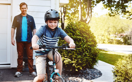 Showing off his biking skills to Dad. a young boy riding a bicycle with his father in the...