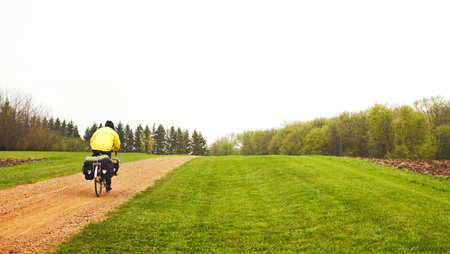 This sure beats cycling in the city. Rearview shot of a male cyclist enjoying a bike ride on a wet winters morning.の写真素材