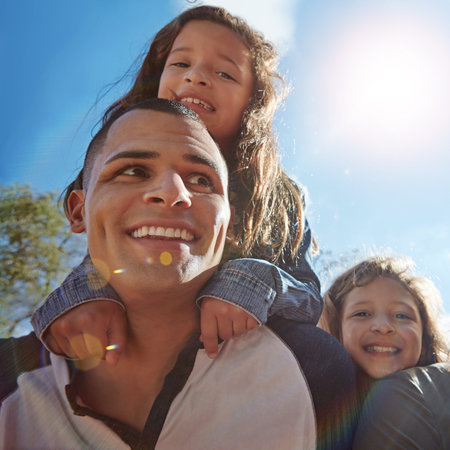Putting his family first. Portrait of a happy young man spending time with his daughters outdoors.