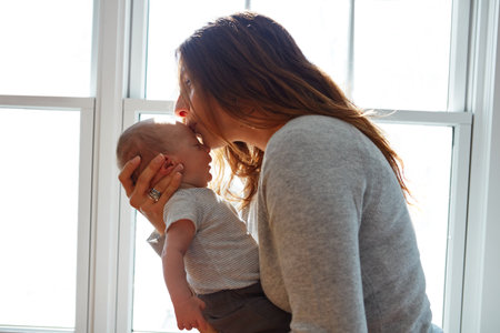 Big kisses from mommy. a mother holding her newborn baby.の写真素材