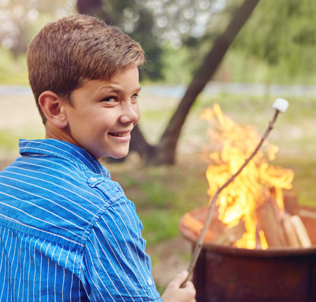 The best campfire treat. a boy roasting marshmallows while camping together.の写真素材