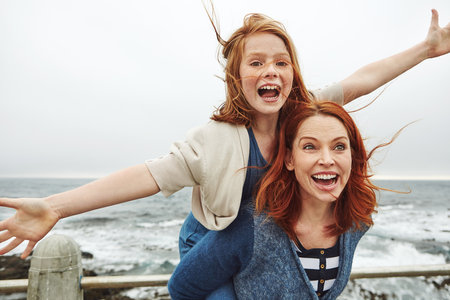 Mommy gives the best piggyback rides. a mother giving her daughter a piggyback ride.の写真素材