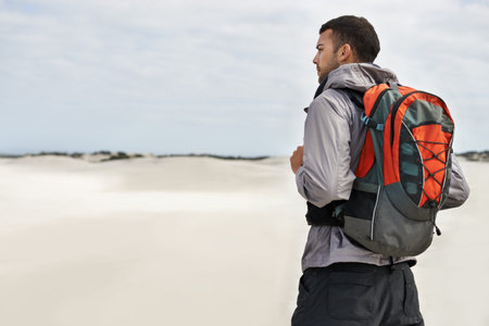 Sometimes life takes you on a journey. a young male hiker walking along the sand dunes.