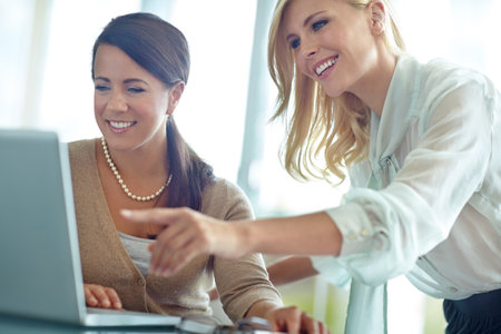What about this concept. Two happy corporate female colleagues looking at something on a laptop.の写真素材