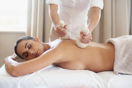 Heat is the way to healing. an attractive enjoying a massage with hot compresses.の写真素材