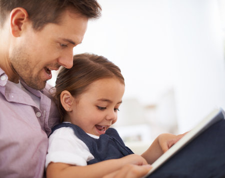 Getting lost in a fairytale. Closeup shot of a young father reading a book with his daughter.の写真素材