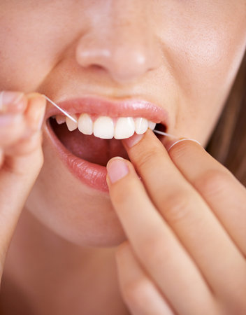Taking care of her teeth. Closeup shot of a young woman flossing her teeth.の写真素材