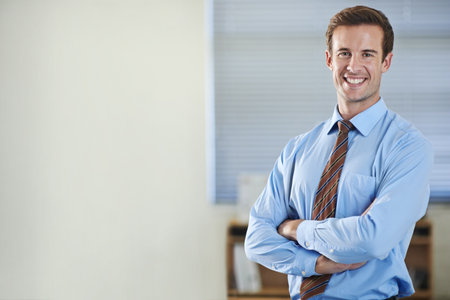 Climbing the corporate ladder. A young businessman standing and smiling with his arms folded - copyspace.の写真素材