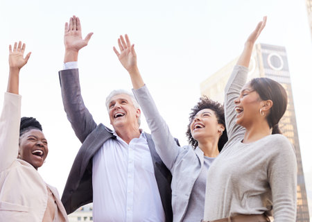 Lets go after success. a diverse group of businesspeople standing outside together with their arms raised.の写真素材