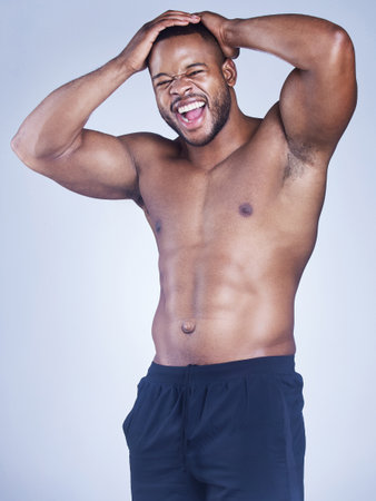 Hard work makes a hard body. Studio shot of a handsome young man posing against a grey background.の写真素材