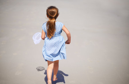 Off to explore with my trusty old net. a little girl running along the beach.の写真素材