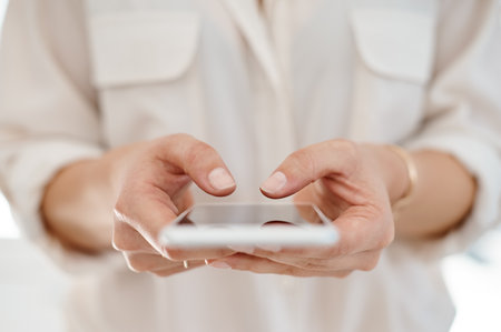 Quickly messaging some of my clients. an unrecognizable businesswoman using her smartphone inside of an office.の写真素材