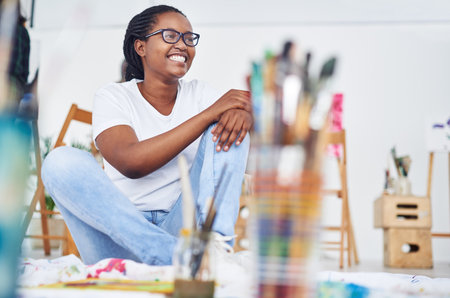 Theres nothing I enjoy more than painting. a happy young woman sitting in a art studio.の写真素材