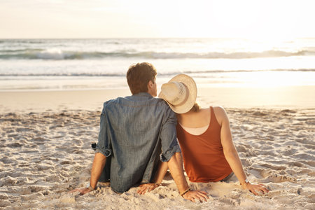 Cherish every sunset. Rearview shot of a middle aged couple watching the sunset on the beach.の写真素材
