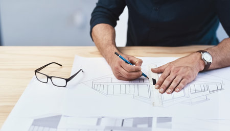 The only way to do it is through creative thinking. an unrecognizable male architect working on a...