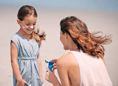 She deserves the best protection. a young mother holding a bottle of suntan lotion at the beach.の写真素材