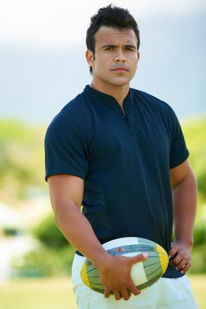 Its a mans sport. Cropped portrait of a young rugby player holding a ball.の写真素材