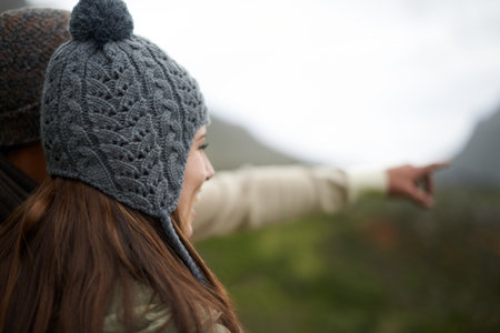 Appreciating the view. A young woman standing outside pointing at something on a cold winters day.の写真素材
