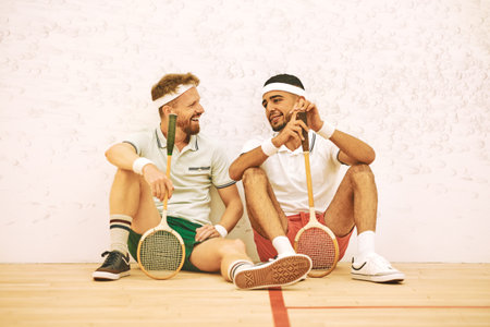 Your game is getting really good. two young men chatting after playing a game of squash.の写真素材