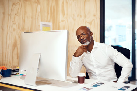 Youll only gain experience through hard work and staying focused. a mature businessman working on a computer in an office.の写真素材