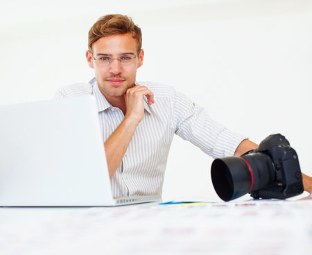 Handsome photographer. Portrait of handsome young photographer using laptop.の写真素材