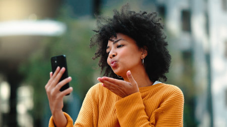 Video call, phone and black woman in city talking online, travel update and 5g communication or funny chat. Laughing gen z person or student on cellphone, mobile and live streaming for urban outdoorの写真素材