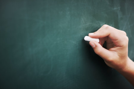 Chalk it up to good education. Cropped image of a young boys hand writing on a blackboard with a...