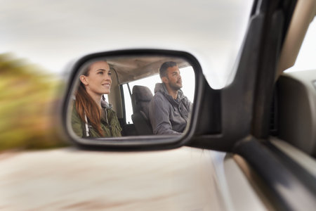 Taking the scenic route. Cropped hot of a young couple on a road trip reflected in a cars side mirror.の写真素材